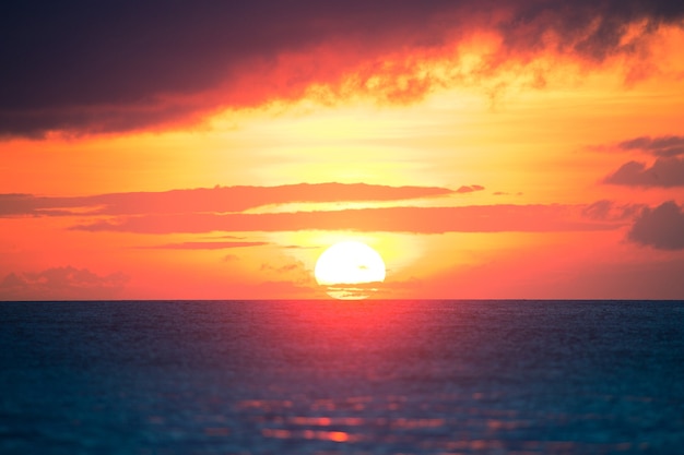 Tramonto colorato di un enorme sole nel mare