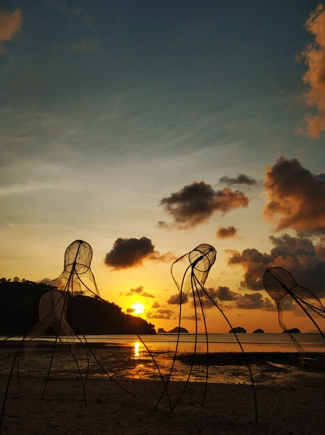 Tramonto colorato sulla spiaggia. Riflessione del cielo al tramonto nell'acqua. Reti da pesca a forma di medusa sulla spiaggia