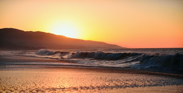 Tramonto con grande sole giallo sotto la superficie del mare oceano calmo con cielo al tramonto e sole attraverso il cl