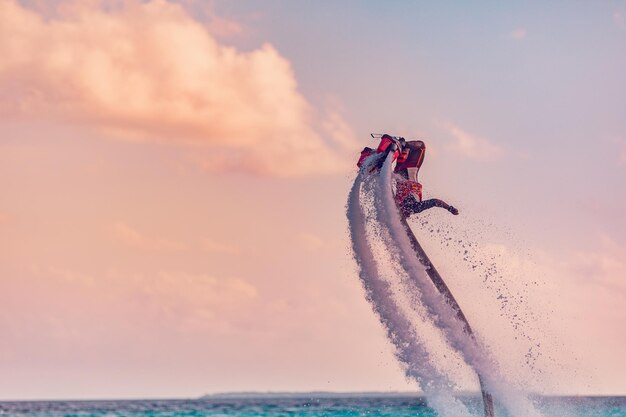 tramonto dell'isola. Pilota professionista della tavola da mosca che fa il back flip con lo sfondo dell'isola di resort tropicale.