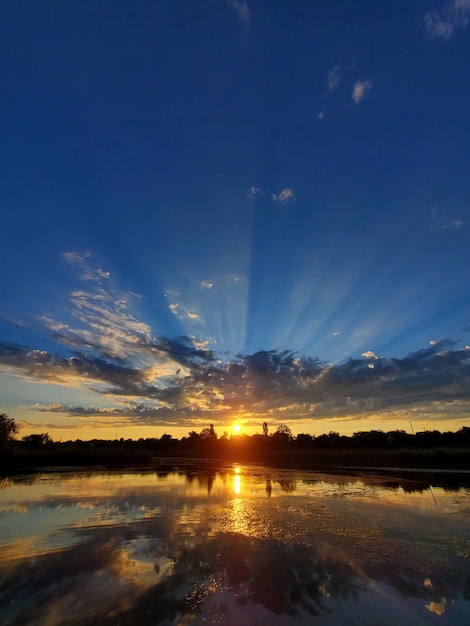 Tramonto di scenario sui raggi di sole lungo il fiume visti nel cielo