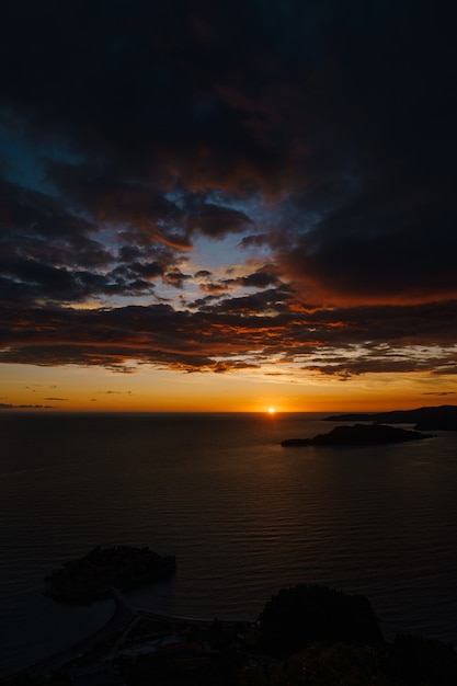 Tramonto dorato ardente nel montenegro sopra il mare vicino a sveti stefan e all'isola di san nicola su