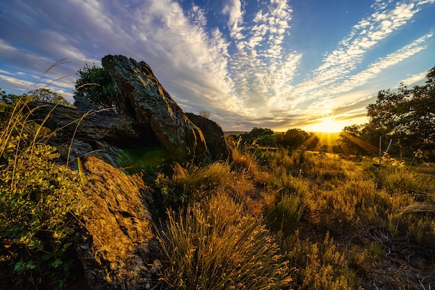 Tramonto dorato con raggi di sole che illuminano le grandi rocce