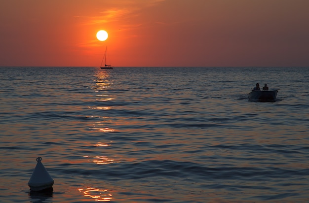 Tramonto in mare con una barca a vela