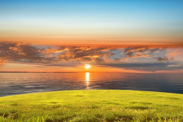 tramonto in mare luce del sole arancione riflesso sull'acqua e sul paesaggio naturale del campo verde selvaggio