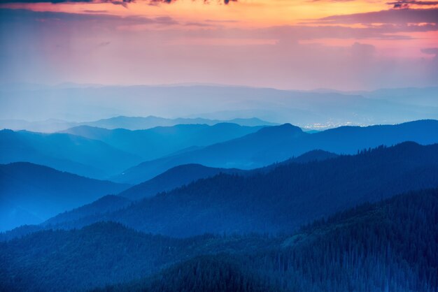 Tramonto in montagna con colline e drammatico cielo colorato