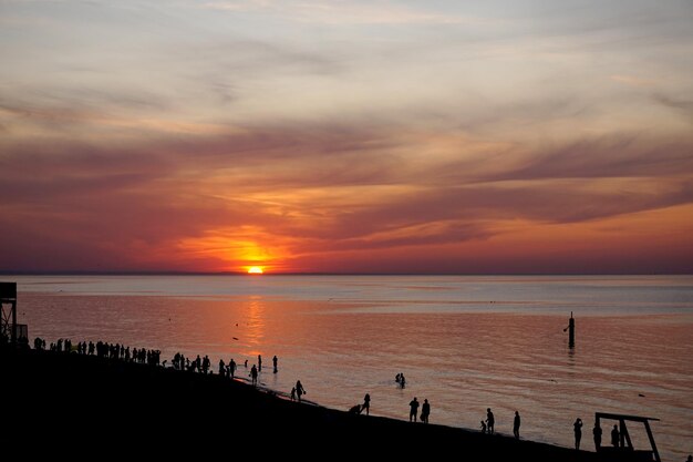 Tramonto in riva al mare con sagome di persone