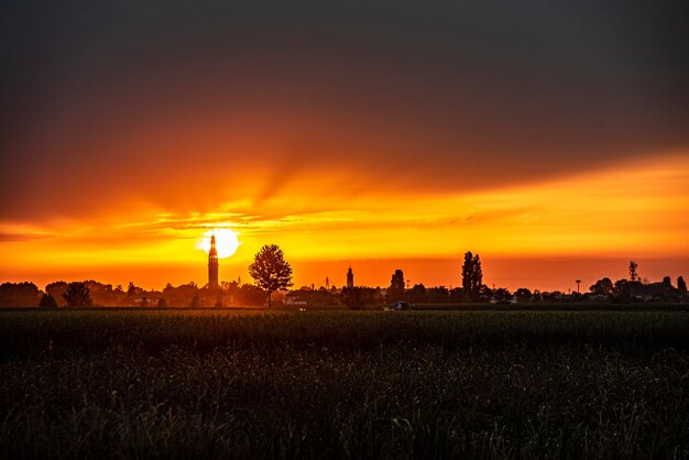 Tramonto in un paesaggio con campanile, alberi e campagna