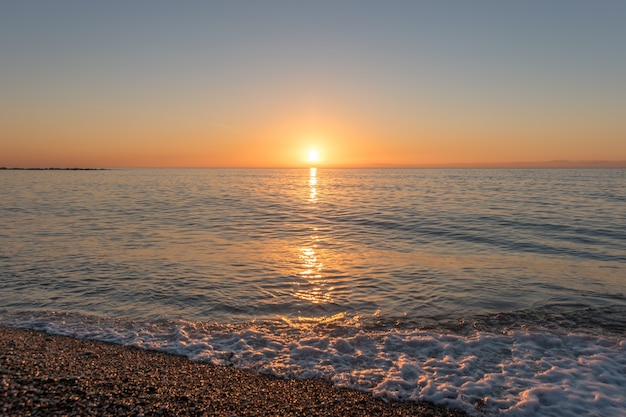 Tramonto luminoso con un sole giallo sopra la superficie del mare