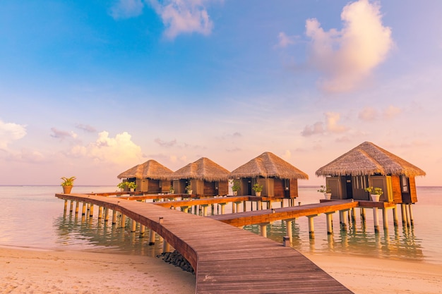 Tramonto nell'isola delle Maldive. Bellissimo cielo e nuvole al tramonto, ville sull'acqua di lusso e sentiero in legno