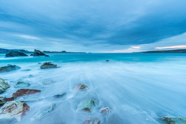 Tramonto nuvoloso sulla spiaggia di Arnao con onde moderate