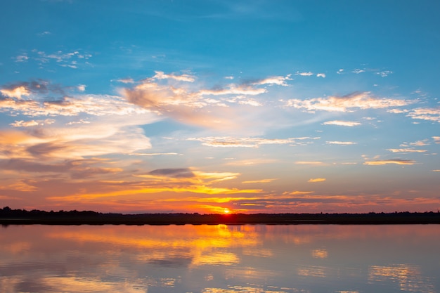 Tramonto riflesso laguna. bel tramonto dietro le nuvole e il cielo blu sopra il paesaggio lagunare. cielo drammatico con nuvole al tramonto