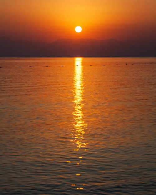 Tramonto rosso in mare sopra le montagne