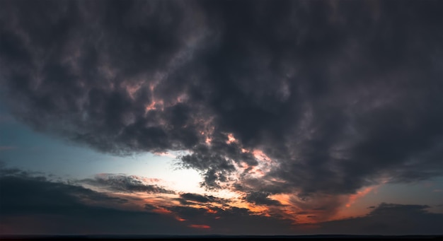 Tramonto scuro con nuvole cupe e luce rossa all'orizzonte