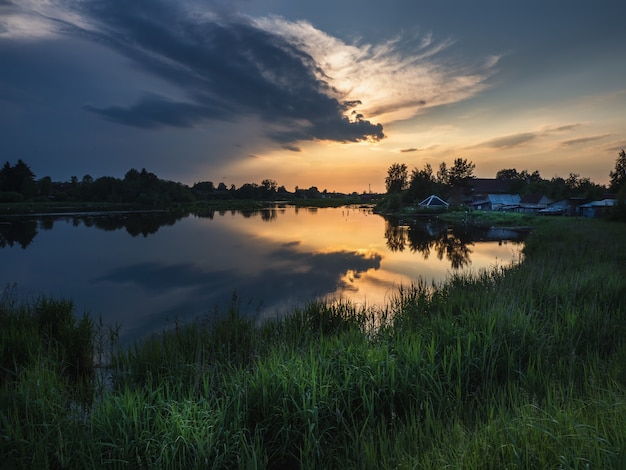 Tramonto sopra il fiume e l'erba alta