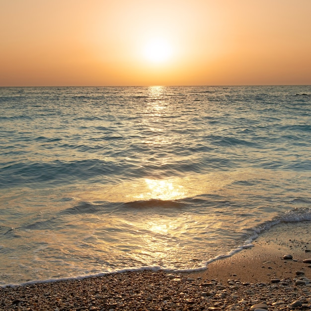 Tramonto sopra il mare. Grande sole e onde in spiaggia