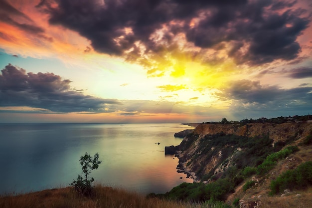 Tramonto spettacolare a capo Fiolent con cespugli di erba e rocce in primo piano