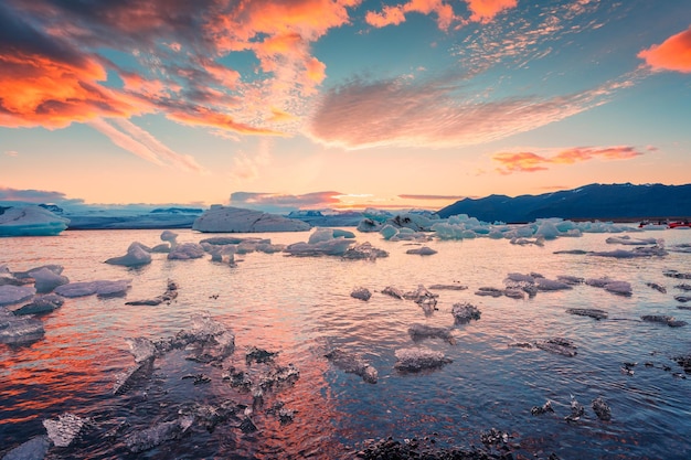 Tramonto su iceberg e rottura del ghiaccio galleggiante nella laguna glaciale di Jokulsarlon Parco nazionale di Vatnajokull in Islanda