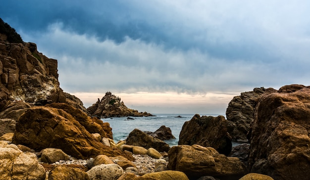 Tramonto su una singola spiaggia piena di rocce.