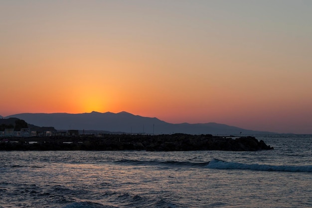 Tramonto sul mare a Kokkini Hani Creta Grecia Il sole scompare dietro la montagna Scenico paesaggio marino di sera