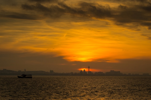 Tramonto sul mare Silhouette della città e la barca da pesca