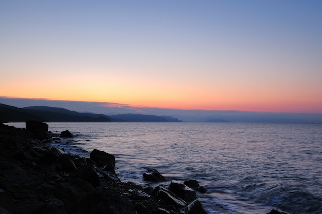 Tramonto sul mare, spiaggia cosparsa di pietre