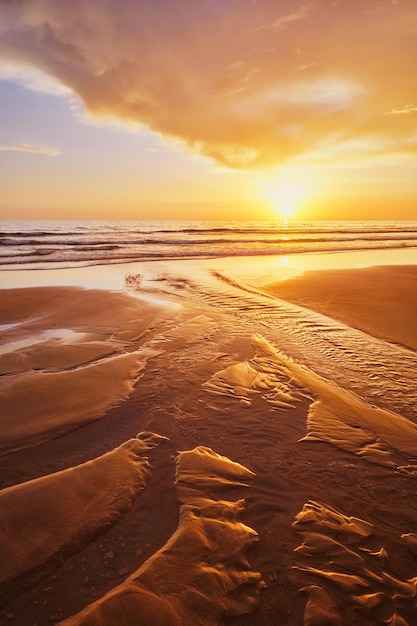 tramonto sull'oceano Atlantico con le onde ondulate sulla spiaggia di Font da Telha, in Portogallo