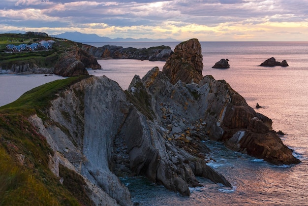 Tramonto sull'Oceano Atlantico costa rocciosa vicino alla spiaggia di Portio (Pielagos, Cantabria, Spagna).