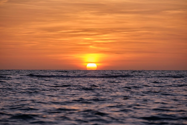 Tramonto sull'oceano Grande sole bianco su sfondo drammatico cielo luminoso morbido orizzonte serale sull'acqua scura del mare