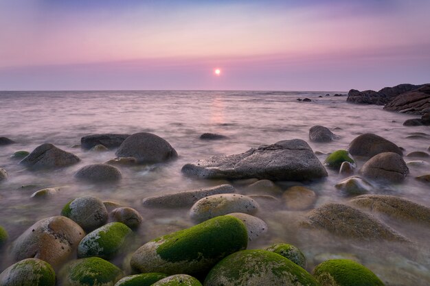 Tramonto sulla costa della Galizia con rocce verdi rotonde