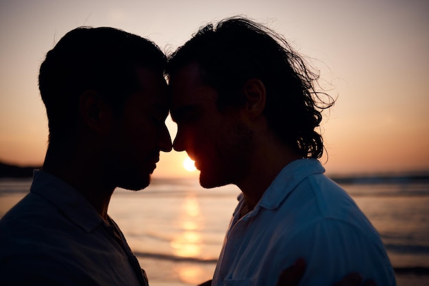 Tramonto sulla spiaggia e coppia gay in silhouette abbraccio e amore durante le vacanze estive sull'isola insieme in Thailandia Sole oceano e romanticismo uomini lgbt nella natura e relax in vacanza con orgoglio mare e luce