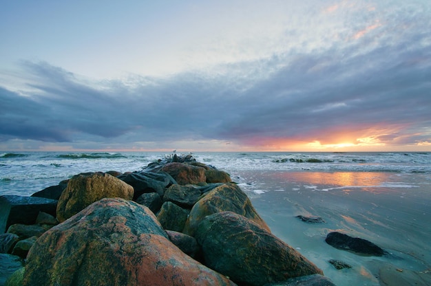 Tramonto sulla spiaggia in Danimarca Groyne di pietra in primo piano Passeggiata sulla costa
