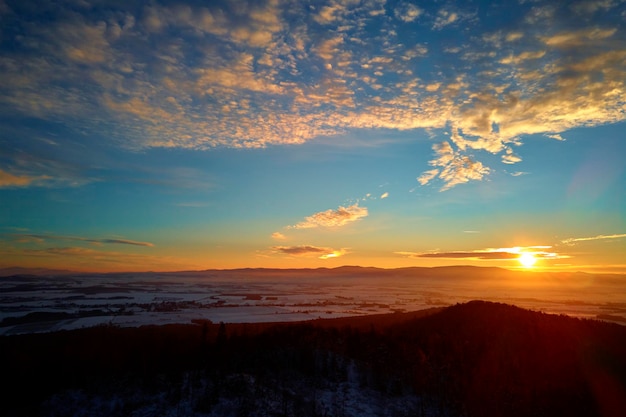 Tramonto sulle montagne con foreste coperte di neve