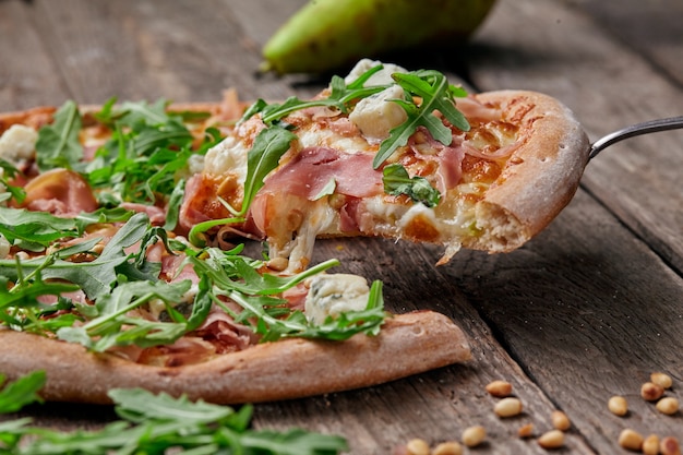 Trancio di pizza con prosciutto crudo gorgonzola pera pinoli rucola