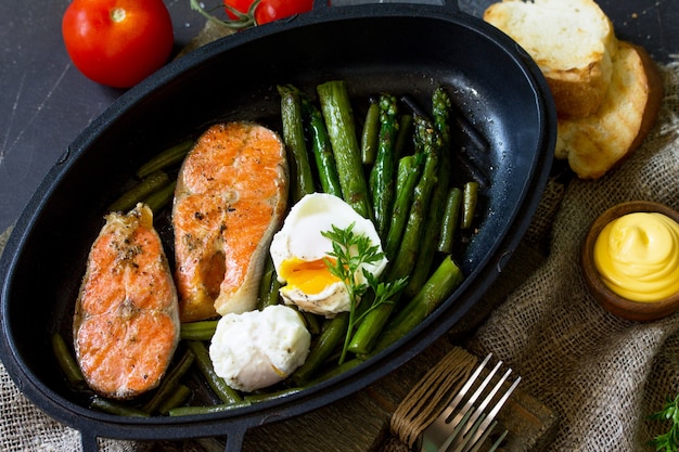 Trancio di salmone alla griglia con asparagi uovo in camicia in padella Cibo sano Vista dall'alto