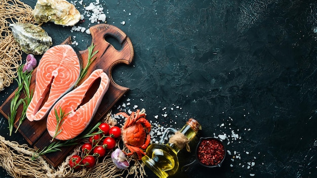 Trancio di salmone crudo con ingredienti su sfondo nero. Vista dall'alto. Spazio libero per il tuo testo.