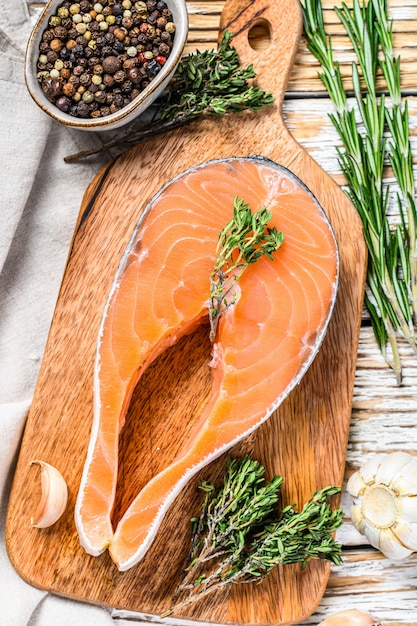 Trancio di salmone crudo fresco con pepe e timo. Spazio in legno bianco. Vista dall'alto