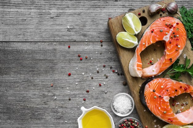 Trancio di salmone ricco di olio di omega 3 con erbe e spezie sul tagliere di legno su fondo di legno rustico