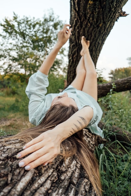 Tranquillità che respira aria fresca da sola donna in abito sdraiato sull'albero