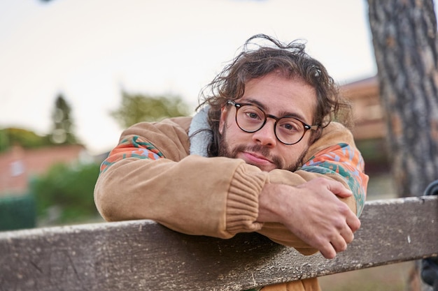 Trans o uomo non binario appoggiato su una panchina che guarda la telecamera