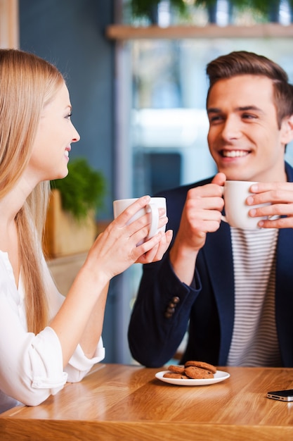 Trascorrere del buon tempo insieme. Bella giovane coppia che parla tra di loro e sorride mentre si gode un caffè al bar insieme