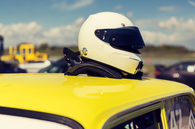 trasporto, alta velocità, corsa e concetto di strada - primo piano dell'auto sull'autodromo o parcheggio con casco sul tetto