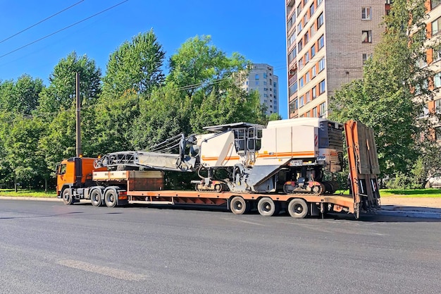 Trasporto di attrezzature per il taglio e la rimozione della vecchia pavimentazione in asfalto per la piattaforma del camion di riparazione stradale di un rimorchio per camion sull'autostrada in una città