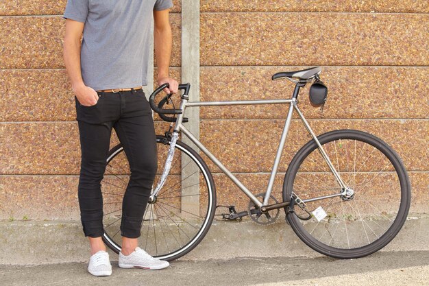 Trasporto ecologico Un'immagine ritagliata di un giovane in piedi accanto a una bicicletta