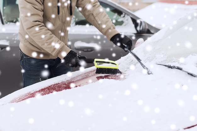 trasporto, inverno, persone e concetto di veicolo - primo piano dell'uomo che pulisce la neve dall'auto con la spazzola