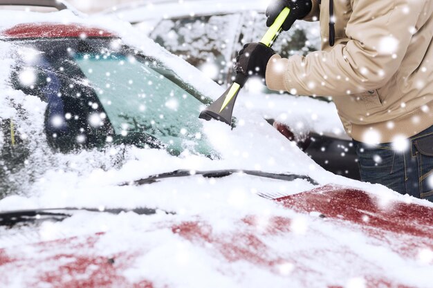 trasporto, inverno, tempo, persone e concetto di veicolo - primo piano dell'uomo che pulisce la neve dal parabrezza dell'auto con una spazzola