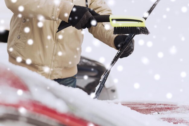 trasporto, inverno, tempo, persone e concetto di veicolo - primo piano dell'uomo che pulisce la neve dal parabrezza dell'auto con una spazzola