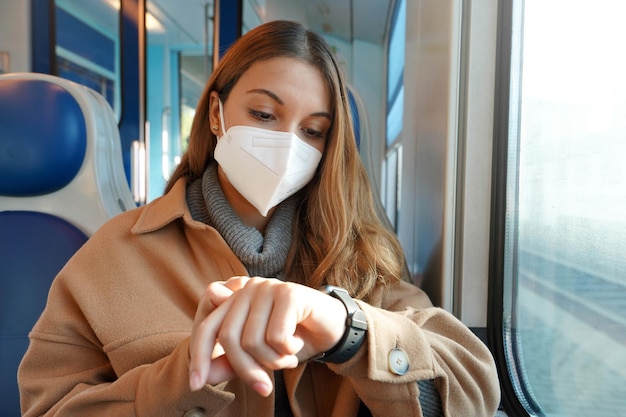 Trasporto pubblico in ritardo. Donna d'affari sul treno guardando smartwatch mentre il suo treno è fermo sulla ferrovia nel bel mezzo del nulla. Persone e il ritardo con il trasporto.