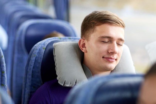 trasporto, turismo, viaggio su strada e concetto di persone - giovane felice che dorme in autobus da viaggio con cuscino