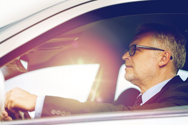 trasporto, viaggio di lavoro e concetto di persone - uomo d'affari anziano felice che guida l'auto